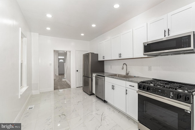 kitchen with white cabinets, appliances with stainless steel finishes, marble finish floor, a sink, and recessed lighting