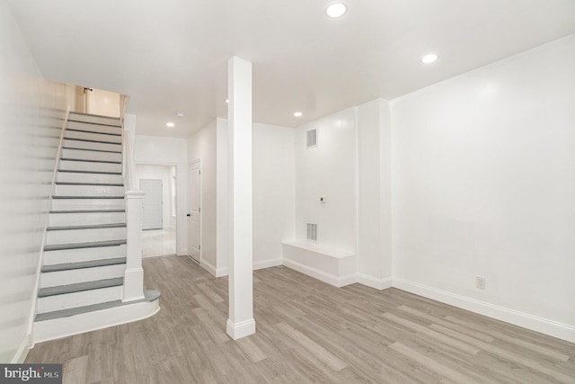 finished below grade area featuring stairway, visible vents, wood finished floors, and recessed lighting