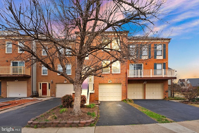 townhome / multi-family property with brick siding, an attached garage, and driveway