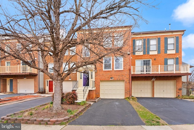 multi unit property featuring aphalt driveway, an attached garage, and brick siding