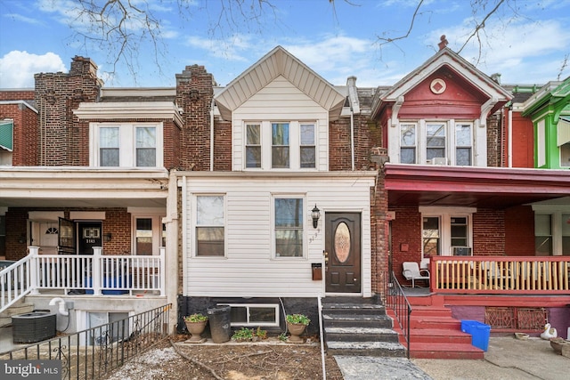 townhome / multi-family property featuring central AC, a porch, and brick siding