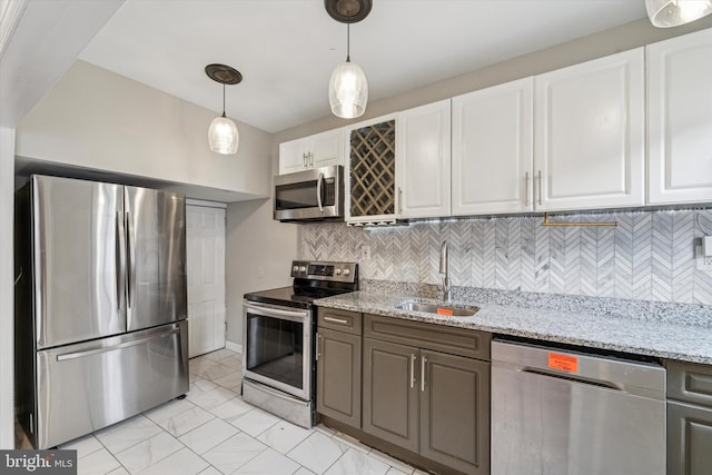 kitchen with tasteful backsplash, decorative light fixtures, stainless steel appliances, white cabinetry, and a sink