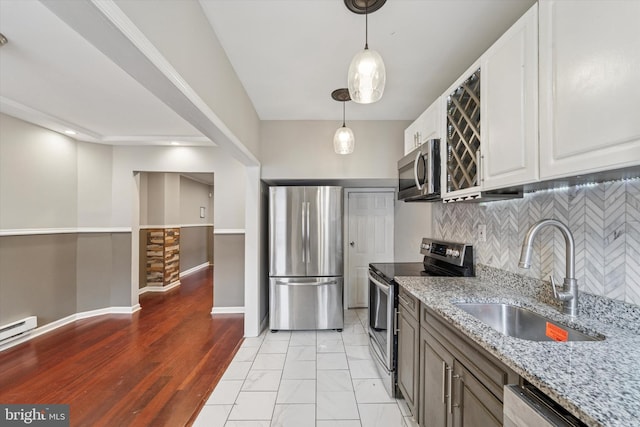 kitchen with light stone counters, backsplash, appliances with stainless steel finishes, white cabinetry, and a sink