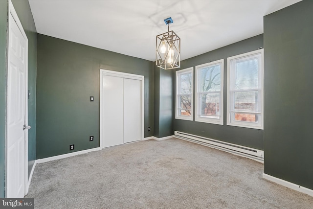 carpeted spare room featuring a baseboard radiator, an inviting chandelier, and baseboards