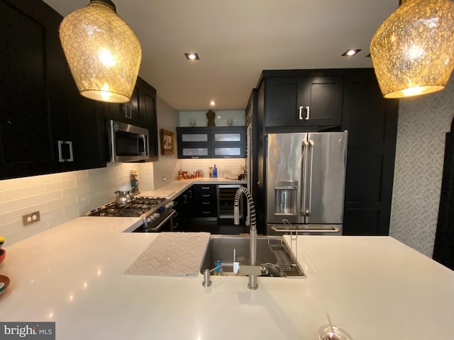 kitchen with a sink, appliances with stainless steel finishes, light countertops, and dark cabinetry