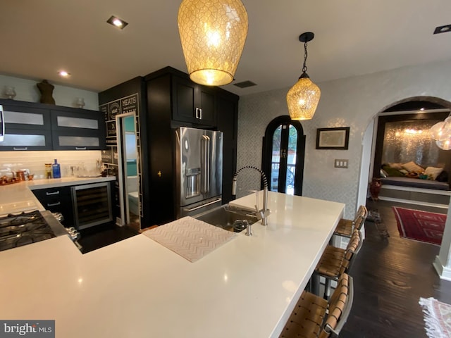 kitchen with arched walkways, visible vents, a sink, beverage cooler, and stainless steel fridge