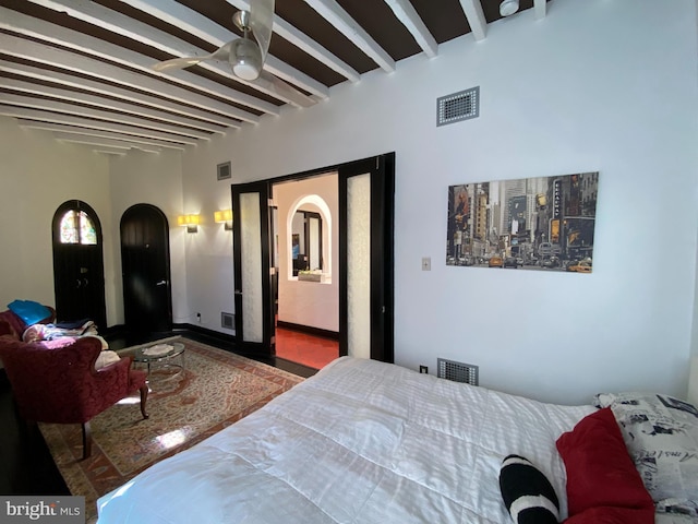 bedroom featuring visible vents, arched walkways, and beam ceiling