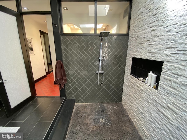 bathroom featuring tile patterned flooring, a tile shower, and baseboards