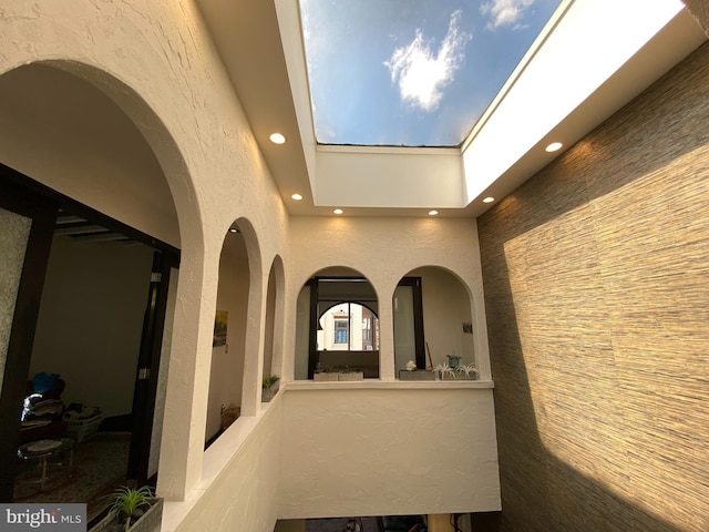 interior space featuring a textured wall, a skylight, a towering ceiling, and recessed lighting