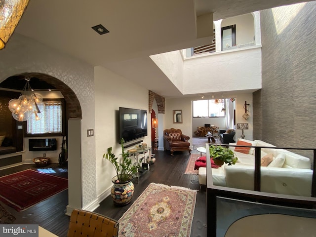 living area featuring baseboards, a notable chandelier, arched walkways, and wood finished floors