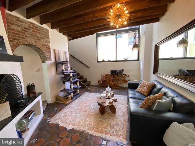 living area featuring arched walkways, beam ceiling, a healthy amount of sunlight, and stairs