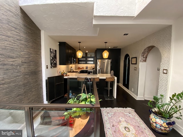 living area featuring arched walkways, dark wood finished floors, and baseboards