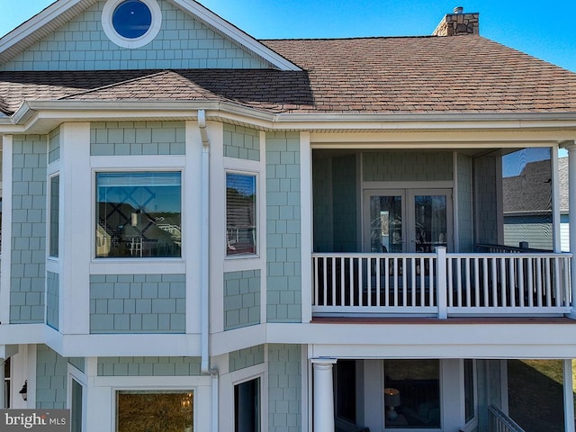 view of side of home featuring a shingled roof and a chimney