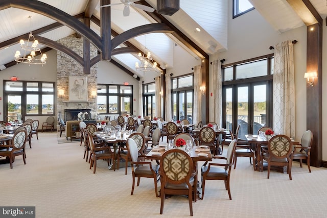 carpeted dining area with french doors, a fireplace, a wealth of natural light, and a notable chandelier