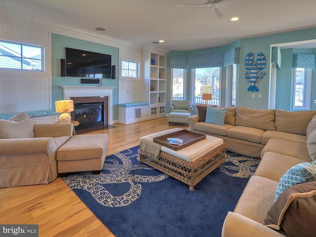 living room featuring a fireplace with flush hearth, a wealth of natural light, and wood finished floors