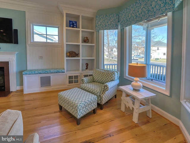 sitting room with a fireplace with flush hearth, light wood-type flooring, and baseboards