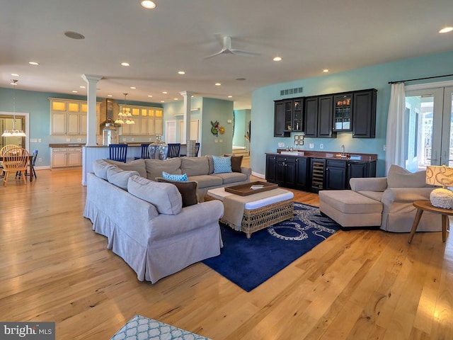 living room featuring decorative columns, recessed lighting, visible vents, light wood-style floors, and beverage cooler