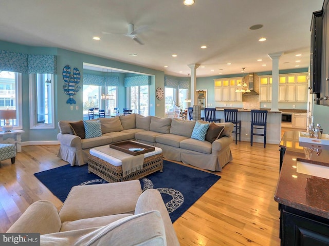 living room with recessed lighting, decorative columns, light wood-style flooring, and baseboards