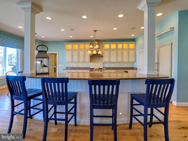 kitchen with light wood-style flooring, glass insert cabinets, decorative columns, and recessed lighting