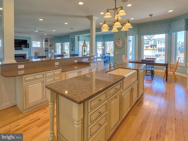 kitchen with plenty of natural light, a large island, cream cabinets, light wood-type flooring, and a sink