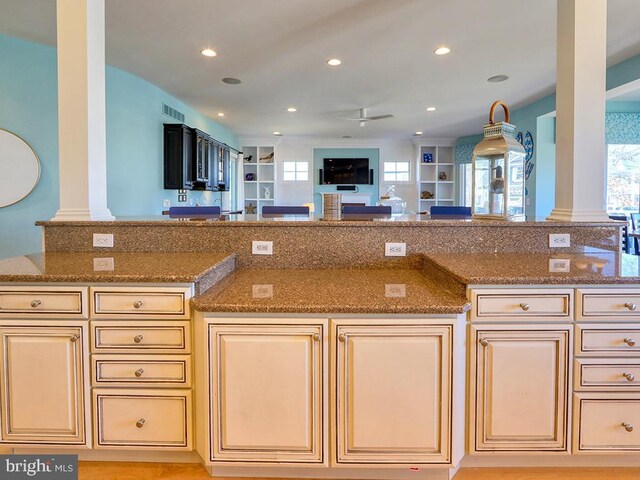 kitchen with stone counters, recessed lighting, visible vents, cream cabinets, and open floor plan