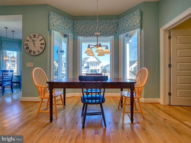 dining space featuring a notable chandelier, light wood-style flooring, and baseboards