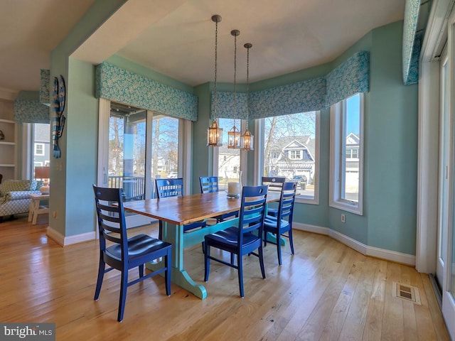 dining room with a chandelier, light wood finished floors, baseboards, and a healthy amount of sunlight