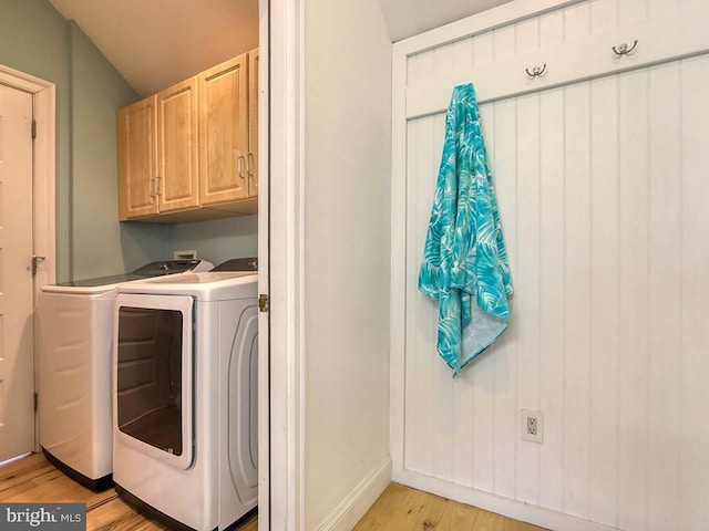 clothes washing area featuring cabinet space, light wood-style flooring, baseboards, and separate washer and dryer