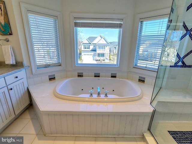 full bath with a jetted tub, tile patterned flooring, tiled shower, and vanity