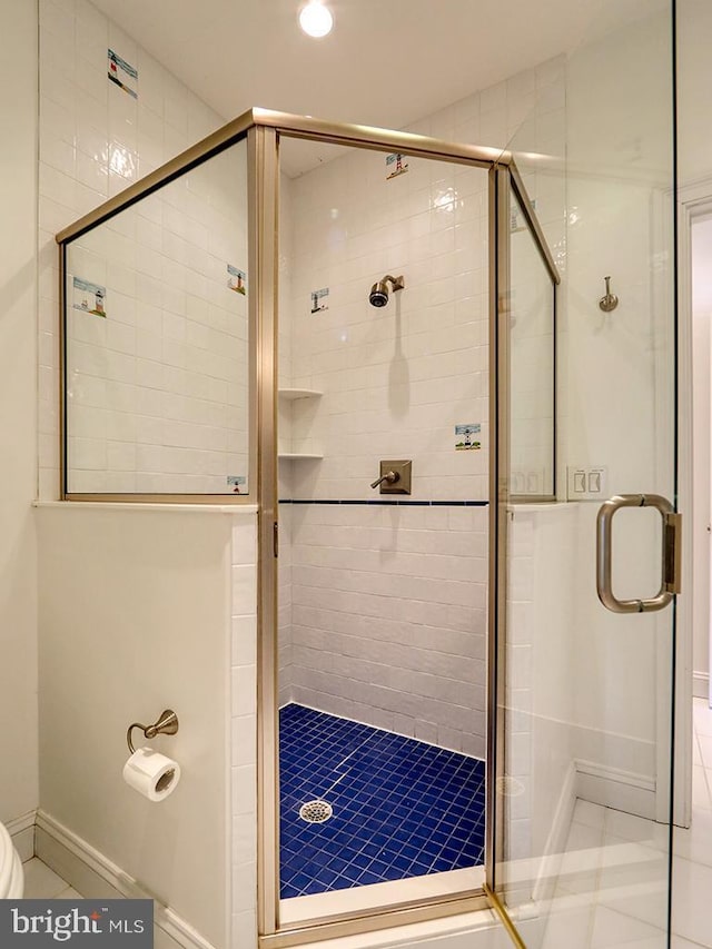 full bath featuring toilet, a shower stall, baseboards, and tile patterned floors