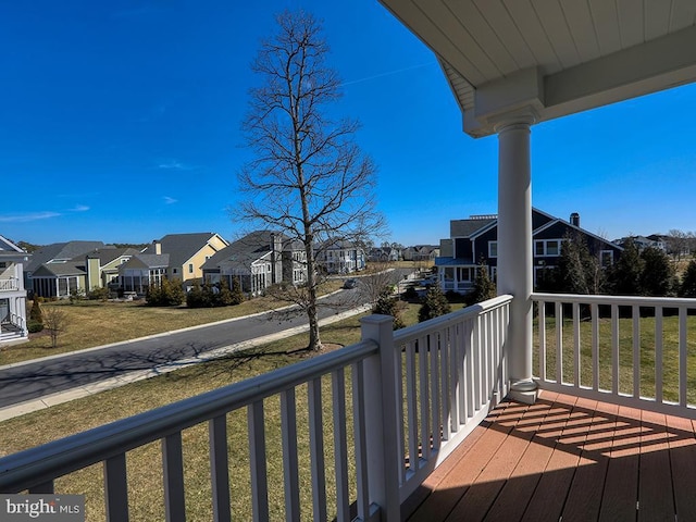 wooden terrace with a residential view and a lawn