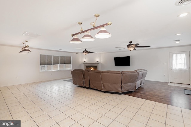 unfurnished living room with visible vents, ornamental molding, a ceiling fan, and light tile patterned flooring