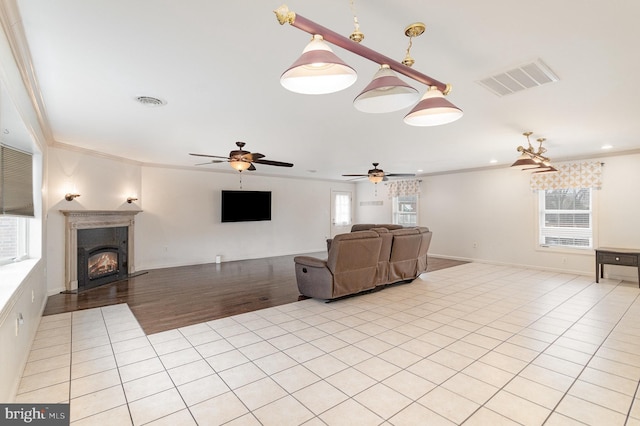 unfurnished living room with a healthy amount of sunlight, visible vents, crown molding, and light tile patterned floors