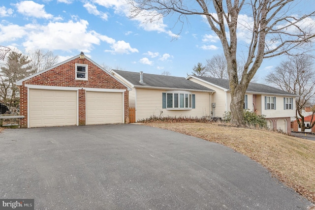 single story home featuring an attached garage, aphalt driveway, and brick siding