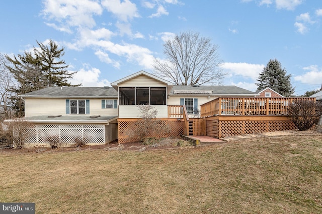 rear view of property featuring a sunroom, a lawn, and a wooden deck