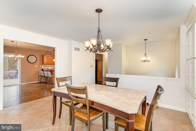 dining space featuring baseboards, visible vents, and a notable chandelier