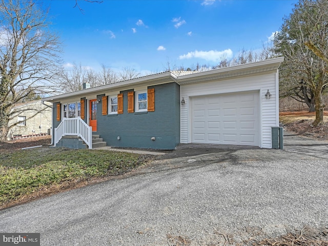 ranch-style house featuring a garage, brick siding, and aphalt driveway