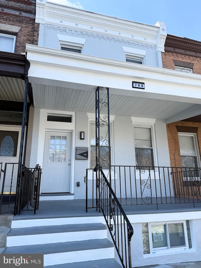 view of exterior entry featuring a porch and brick siding