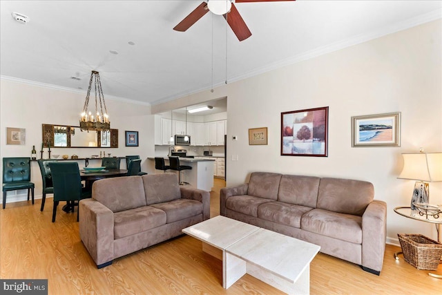 living area featuring light wood-style flooring, ornamental molding, and ceiling fan with notable chandelier