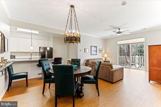 dining area with light wood-style floors, visible vents, a ceiling fan, and crown molding