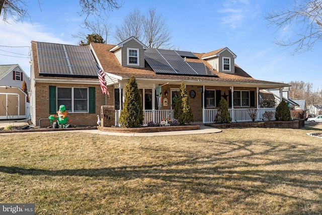 view of front facade featuring a porch, brick siding, a front lawn, and solar panels