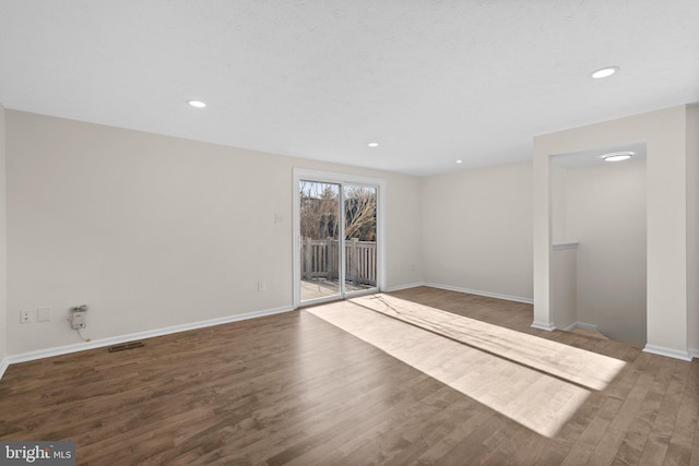 empty room with recessed lighting, visible vents, baseboards, and wood finished floors