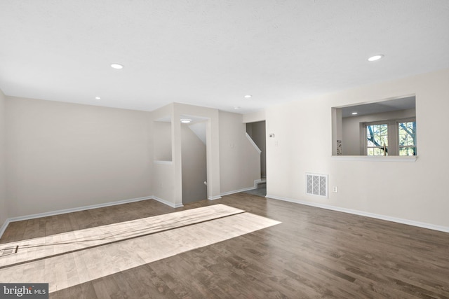 interior space featuring wood finished floors, visible vents, baseboards, recessed lighting, and stairs