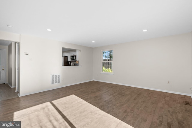 unfurnished living room with visible vents, baseboards, and wood finished floors