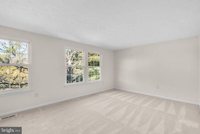 unfurnished room with visible vents, light colored carpet, and plenty of natural light