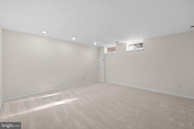 basement with recessed lighting, light colored carpet, baseboards, and a textured ceiling