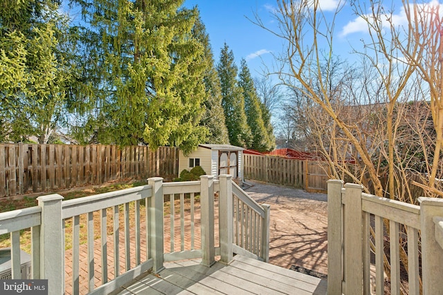 wooden terrace with a storage unit, an outbuilding, and a fenced backyard