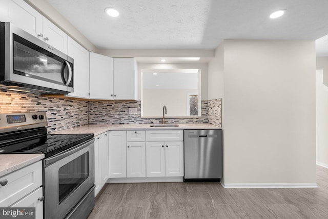 kitchen featuring a sink, backsplash, appliances with stainless steel finishes, and white cabinetry