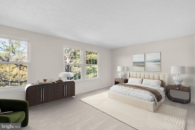 bedroom with multiple windows, light carpet, and baseboards