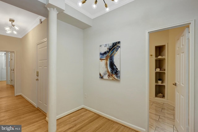 hallway with baseboards, ornamental molding, light wood-style floors, and built in features